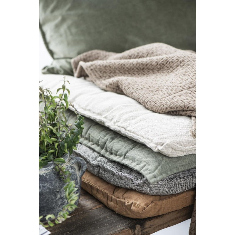 Detaljbilde av rustbrun bomullspute fra IB Laursen på trebord