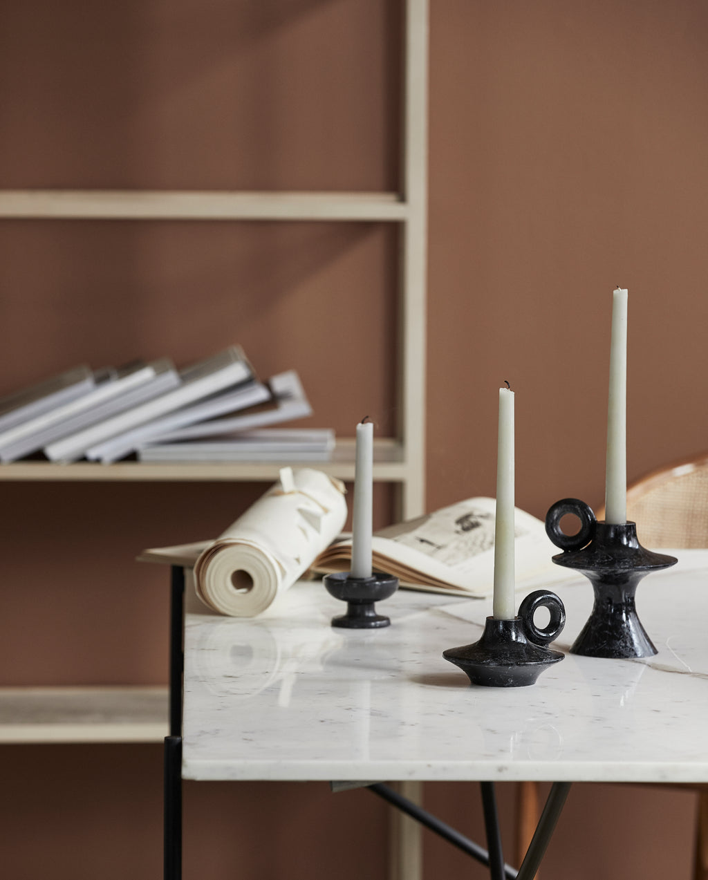 PALAWAN lysestake fra Nordal på bord med stearinlys, kombinert med minimalistisk og rustikk interiør i varme jordtoner.
