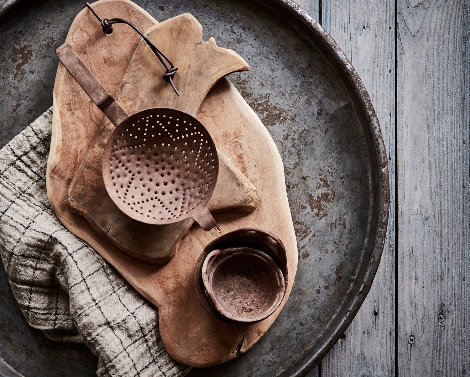  Jernfat med trebrett og keramikk – rustikk styling på bord i nordisk interiør. 