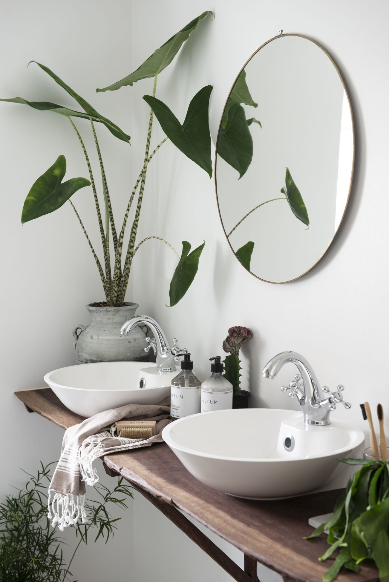 IB Laursen rundt speil i messing på baderomsvegg med grønne planter