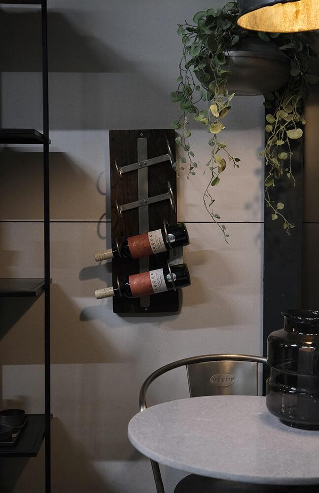 Vegghengt vinholder i mørkt tre og metall – interiørbilde med vinflasker og grønn plante