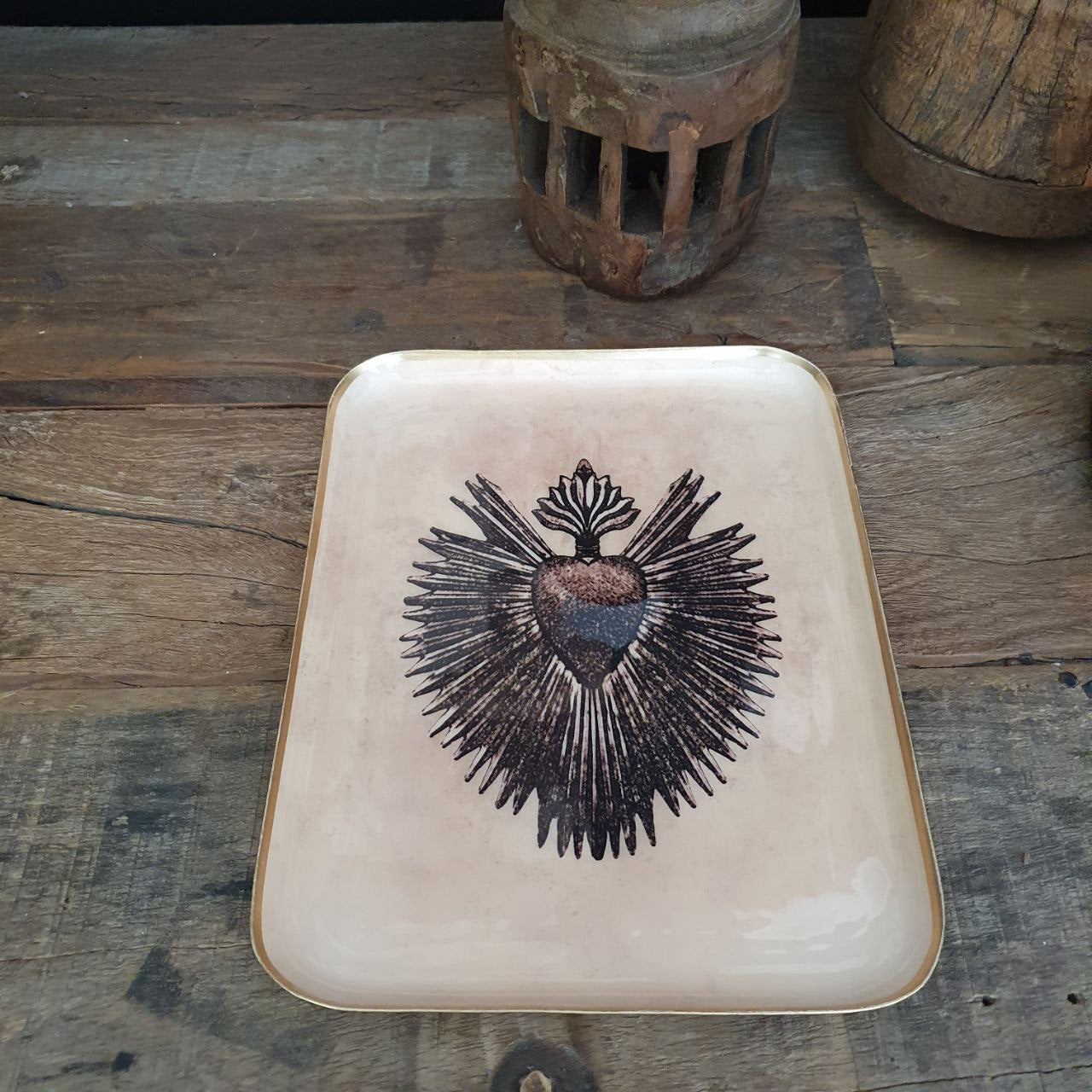 ektangulært dekorbrett i beige med Sacred Heart-motiv og gullkant, plassert på rustikt trebord.